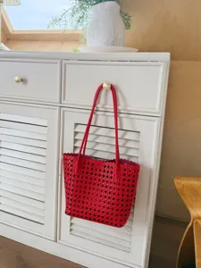 Vue détaillée du sac cabas rouge en cuir tressé avec un design ajouré et une texture.