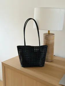 Vue de détail d'un sac cabas noir tissé élégant mettant en valeur sa texture et ses lanières.