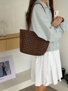 Vue détaillée du sac porté épaule en cuir tressé marron foncé, montrant sa texture souple.
