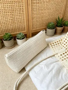 Detail view of a white woven shoulder bag and clutch, featuring a chic braided design and zipper.
