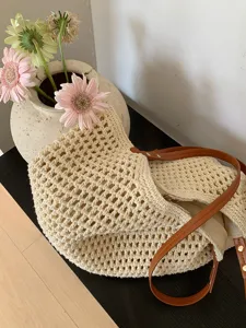 Detail view of the handmade crochet straw tote bag, beige knit texture and brown straps.