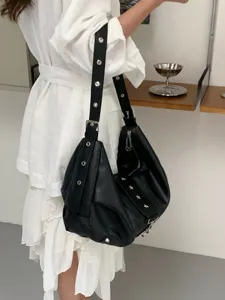Chic black soft leather shoulder bag with metal grommets, casual hobo commuting handbag.