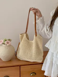 Close-up detail of the handmade woven straw tote bag with brown straps, stylish summer beach handbag.