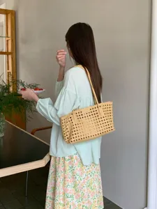 Detailed lifestyle view of a chic hollow woven shoulder bag, perfect for summer vacation chic.