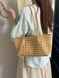 Detailed view of a fashionable hollow woven tote bag, ideal for summer vacation.