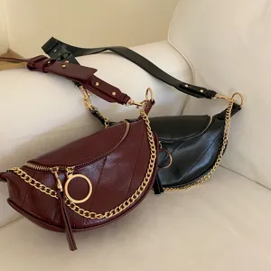 Detailed shot of trendy women crescent waist bag with metallic chain and zipper decoration.
