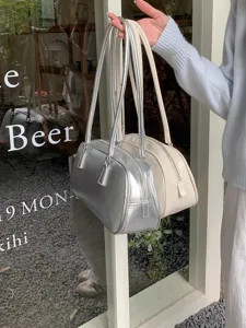 Detail shot of stylish metallic silver and beige shoulder handbags with zipper closure.