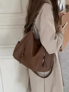 Detailed view of a brown leather underarm shoulder bag with zipper pockets and strap.