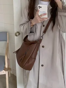 Detail view of a brown vintage leather crossbody shoulder bag worn by model, casual OOTD.