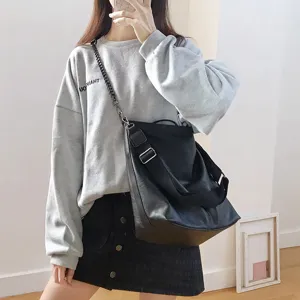 Detailed view of a versatile black PU leather bucket bag with chain strap worn by model.