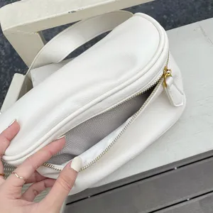 White soft leather crossbody bag detail, wide strap, zipper closure and inner lining texture.