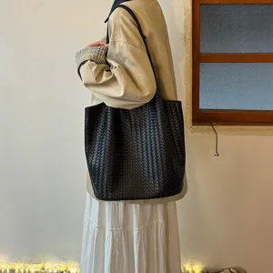 Detail view of the black woven tote bag showcasing premium leather texture and chic design.