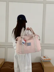 Dettaglio borsa da viaggio rosa mostra cinghie robuste e un grazioso design con ciondolo.