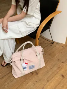 Dettaglio borsa da viaggio in tela rosa, con manici intrecciati resistenti e tasca frontale.
