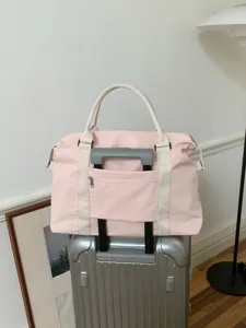 Vista dettagliata della borsa da viaggio rosa con tasca per maniglia del trolley e manici.