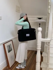 Vista dettagliata della grande borsa da viaggio nera, mostrata su un modello all'interno.