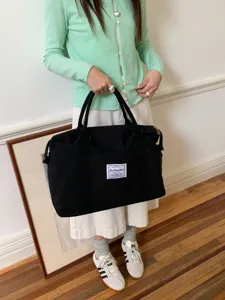 Vista dettagliata della grande borsa da viaggio in tela nera, shopper casual per uso quotidiano.