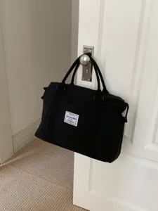 Dettaglio borsa da viaggio in tela nera, borsa weekender di grande capacita per donne.