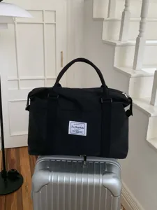 Vista dettagliata della grande borsa da viaggio nera su valigia argentata per brevi viaggi.