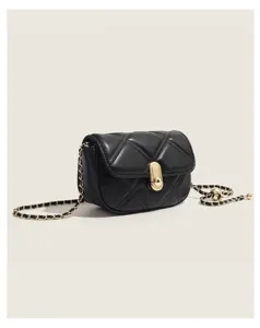 Detail view of black quilted leather crossbody bag with chic golden metal clasp and chain strap.