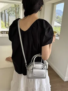 Detail view of a stylish silver metallic crossbody handbag with dual top handles and small pocket.