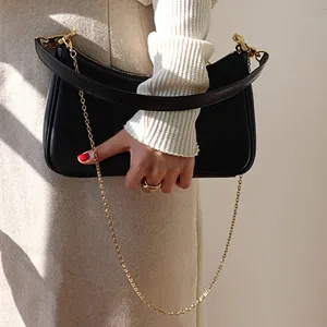 Schwarze Lederschultertasche mit Goldkettenriemen, stilvolle minimalistische Tasche.