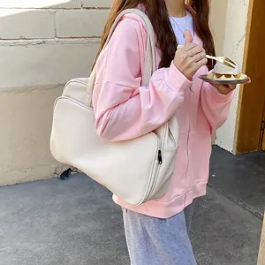 Detailed view of a large capacity cream shoulder bag styled with casual pink streetwear.