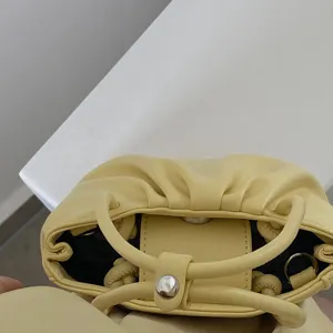 Yellow ruched detail handbag close-up showing clasp closure, soft PU leather and ring handle design.