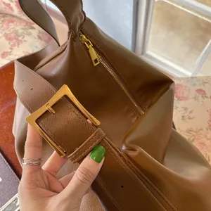 Borsa a tracolla hobo minimalista marrone con dettaglio di fibbia dorata e zip.