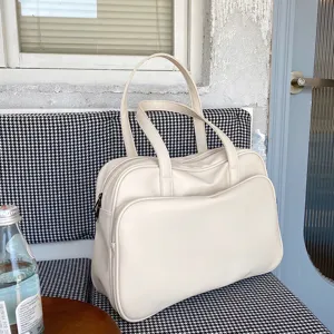 Detailed view of a large capacity beige leather tote shoulder bag resting on a patterned seat.