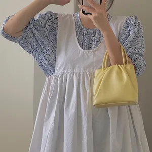 Detail view of a trendy pastel yellow pleated handbag, elegant design for summer daily wear.