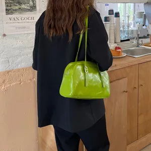 Detailed view of trendy green patent leather shoulder bag with chic double straps and buckles.