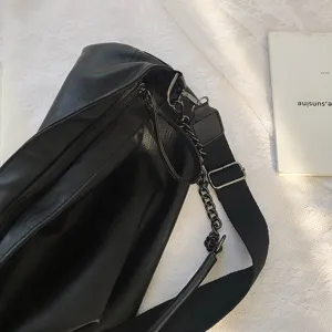 Black leather crossbody shoulder bag with wide strap and chain detail for women autumn winter.
