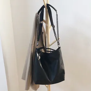 Black PU leather shoulder bag lifestyle detail shot with metallic chain strap and spacious bucket design.