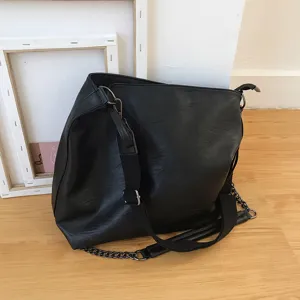 Detailed view of the black PU leather shoulder bag featuring a metallic chain and strap.
