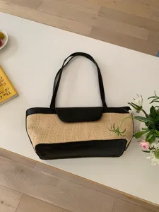 Detailed view of the chic French straw woven shoulder bag with black leather trim.