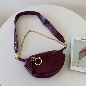 Wine red crescent crossbody chest bag featuring a thick leather strap and elegant gold chain.