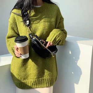 Stylish black waist bag with gold chain detail, worn crossbody by model in green sweater.