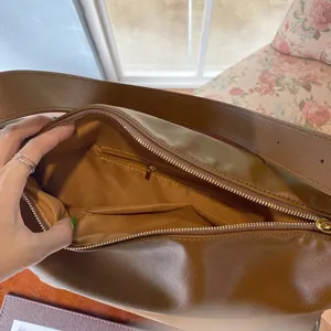 Dettaglio interno della grande borsa a spalla minimalista in pelle marrone con tasca con zip.