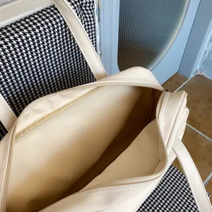Close-up view of a large capacity cream white tote bag with zipper closure, perfect for travel.