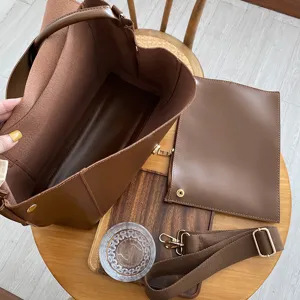 Detailed view of brown leather tote bag interior, matching pouch, and adjustable strap.