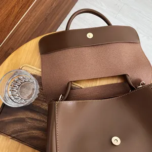 Retro brown leather handbag detail, showing flap closure, smooth texture and spacious interior.