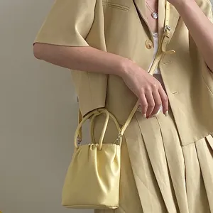 Detail shot of a trendy yellow pleated mini handbag, showing soft texture and handle design.