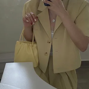 Close-up detail of the butter yellow pleated handbag featuring soft gathered design and handle.