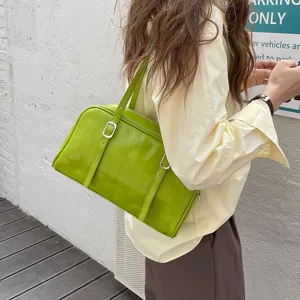 Green leather shoulder bag detail showing stylish metal buckle strap and bright vintage finish.