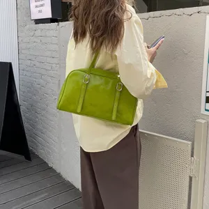Detail view of a retro green shoulder bag, stylish underarm handbag with dual strap accents.