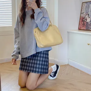 Detailed view of a yellow casual shoulder tote bag in an indoor setting, stylish design.