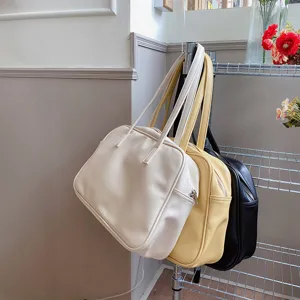Close-up detail shot of casual solid color shoulder bags hanging on a metal rack.