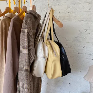 Detail view of stylish minimalist solid color shoulder bags in white, yellow and black.