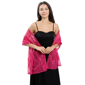Gros plan détaillé du châle en tulle rose avec une broderie florale et des paillettes exquises.